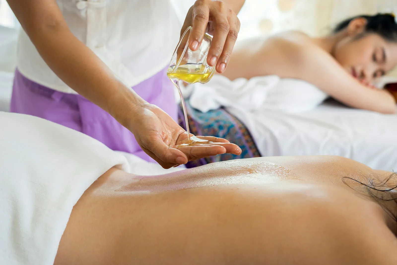 Therapist pouring warm oil for a back massage