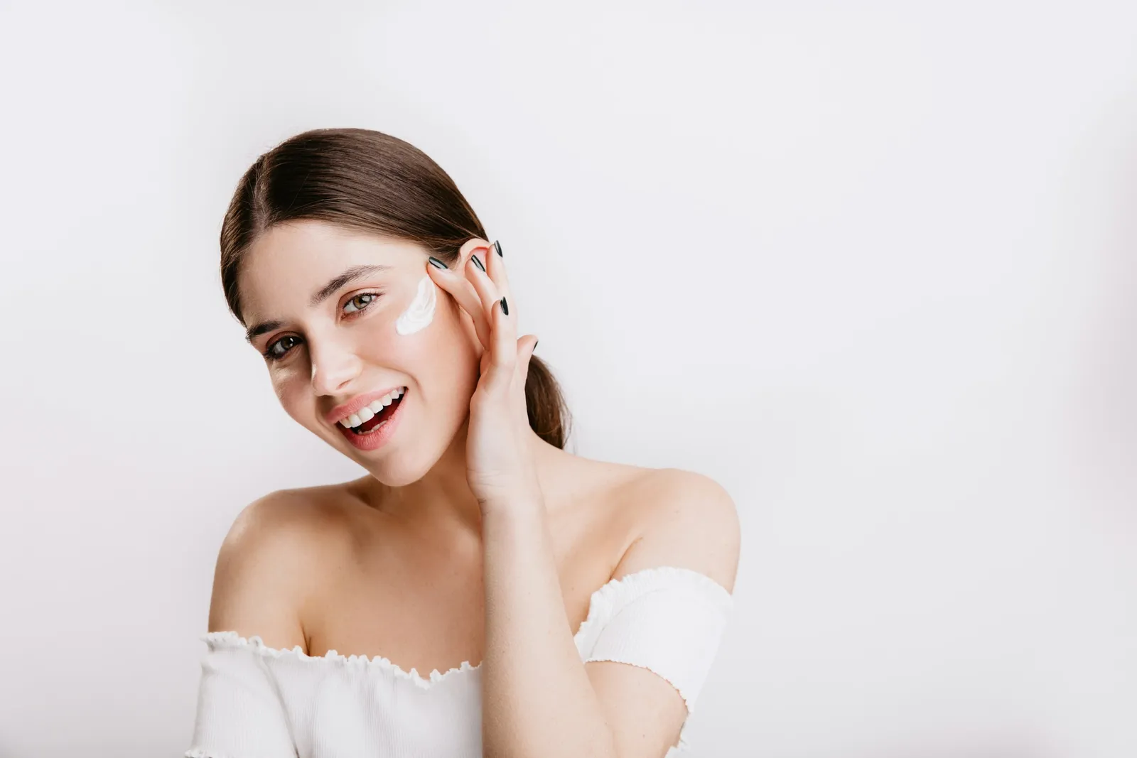 Smiling woman applying moisturiser