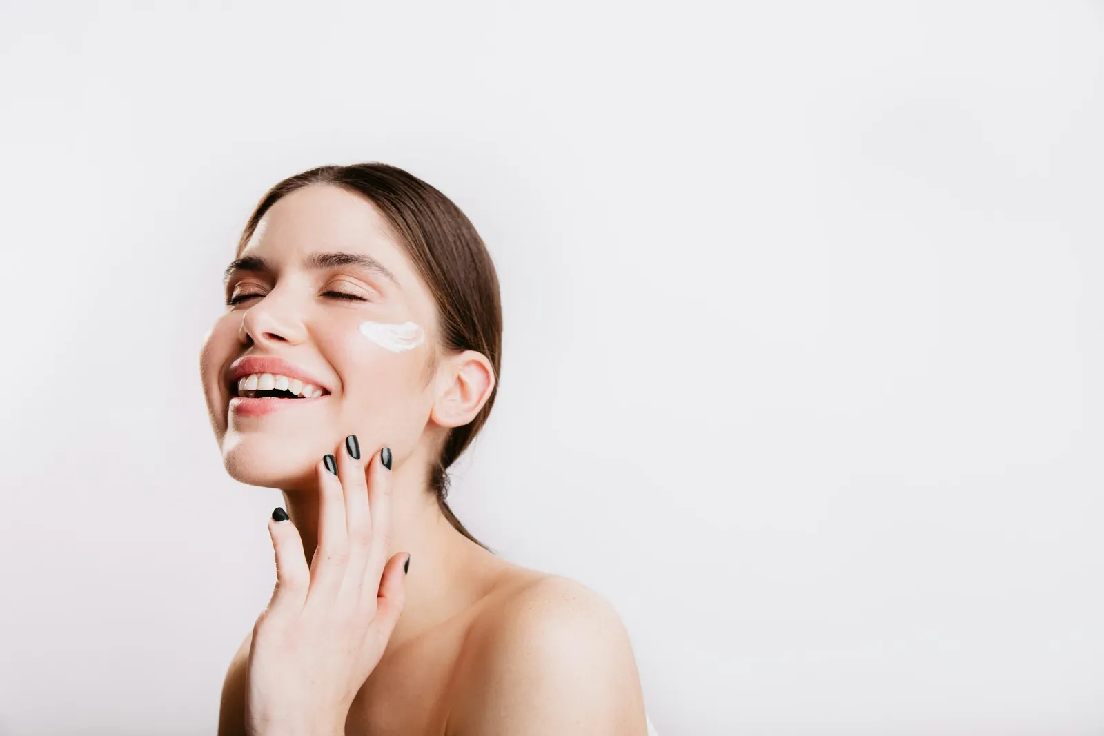 Smiling woman with cream on her cheek