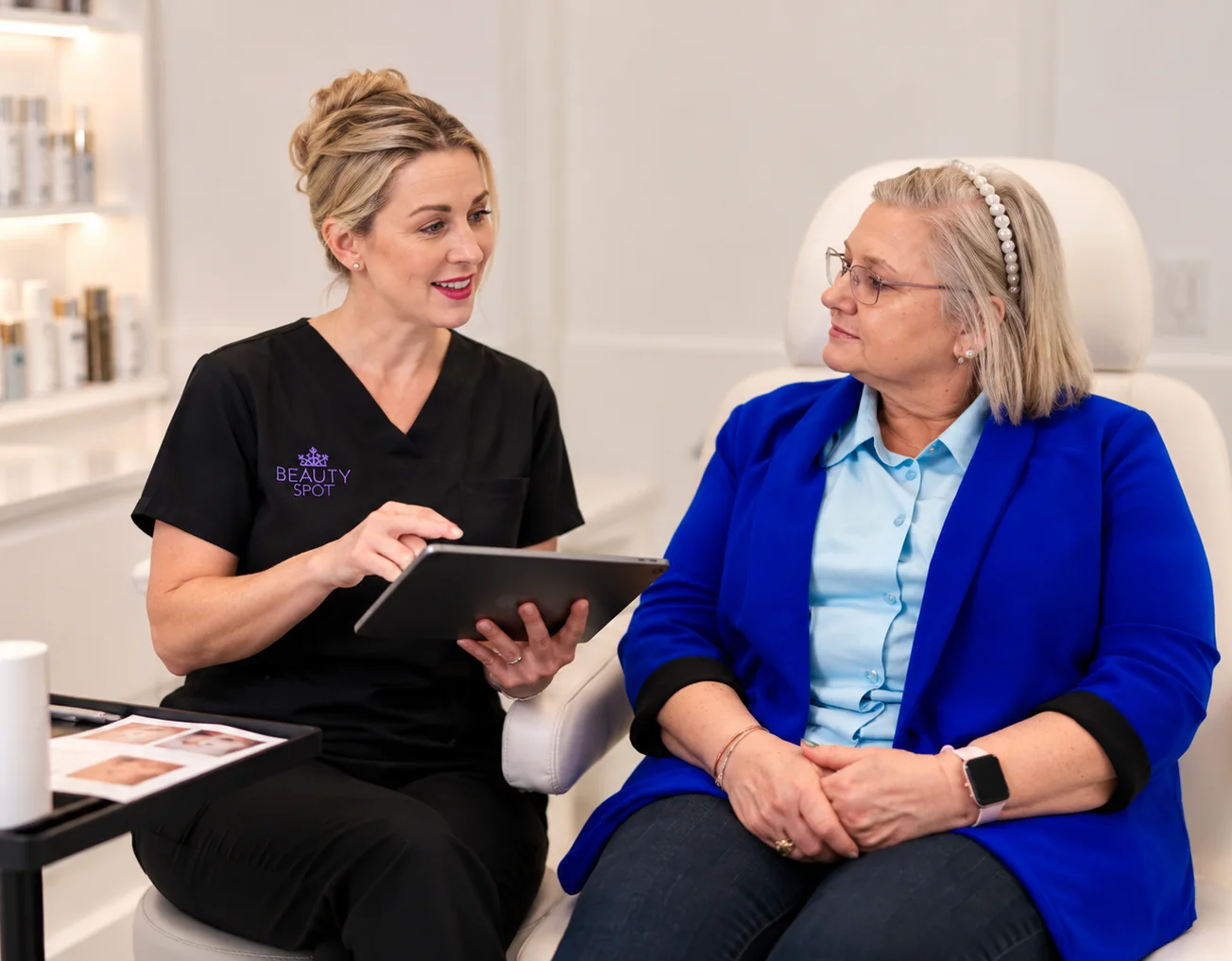 A Beauty Spot therapist talking a client through her treatment plan on a tablet